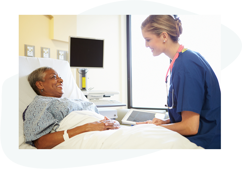 Infirmière tenant une tablette près d'un patient étendu dans un lit d'hôpital, heureuse des résultats de ses soins