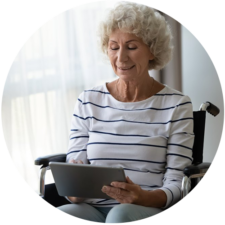 Elderly lady in wheelchair using tablet to read about virtual complex care