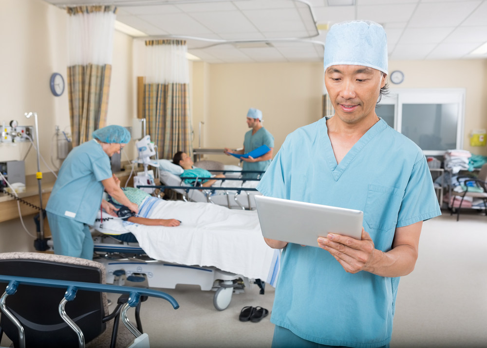 Male doctor in recovery room on iPad