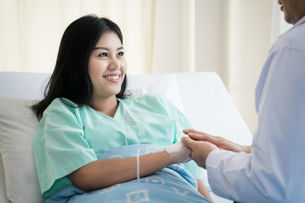 Hand,Of,Man,Doctor,Reassuring,His,Female,Patient,In,Bed